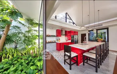 Luxurious modern kitchen with red cabinets and large island, adjacent to lush indoor garden.