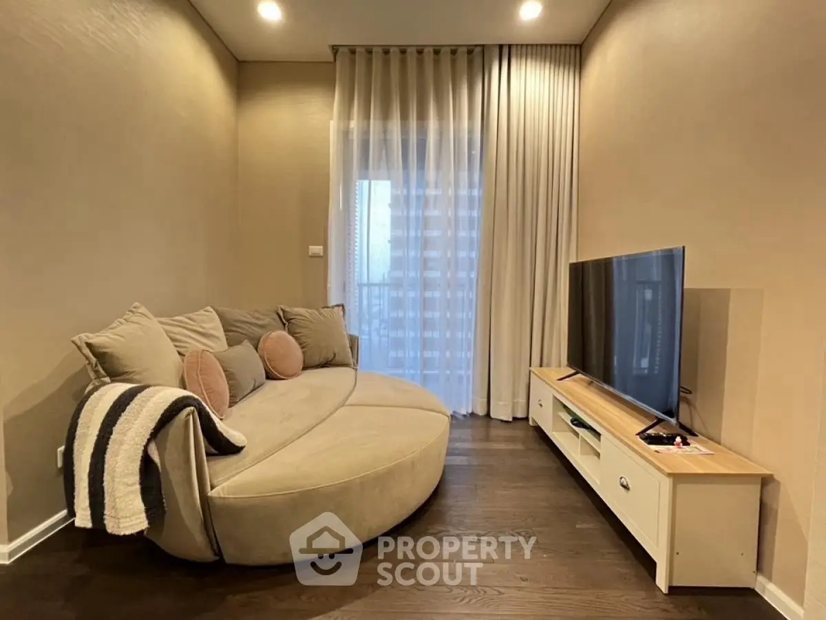 Cozy living room with modern round sofa and sleek TV setup, perfect for relaxation.