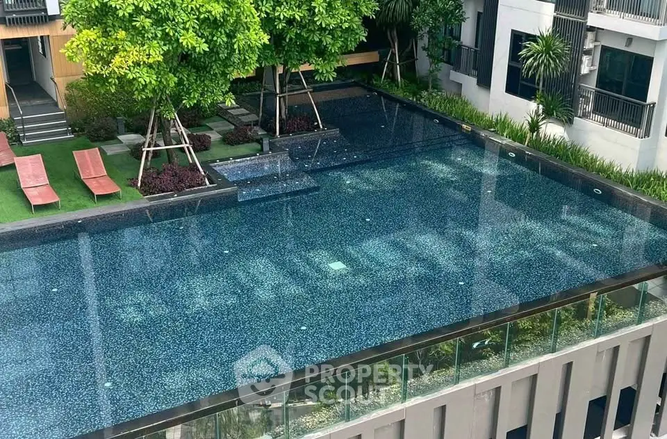 Luxurious apartment complex with stunning rooftop infinity pool and lush greenery.