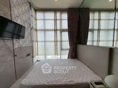 Cozy bedroom with large windows and wall-mounted TV, perfect for relaxation.