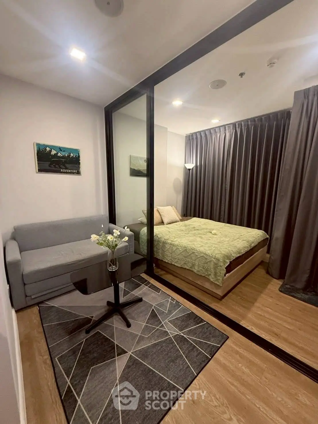 Modern compact living room with glass partitioned bedroom, stylish decor and cozy ambiance.