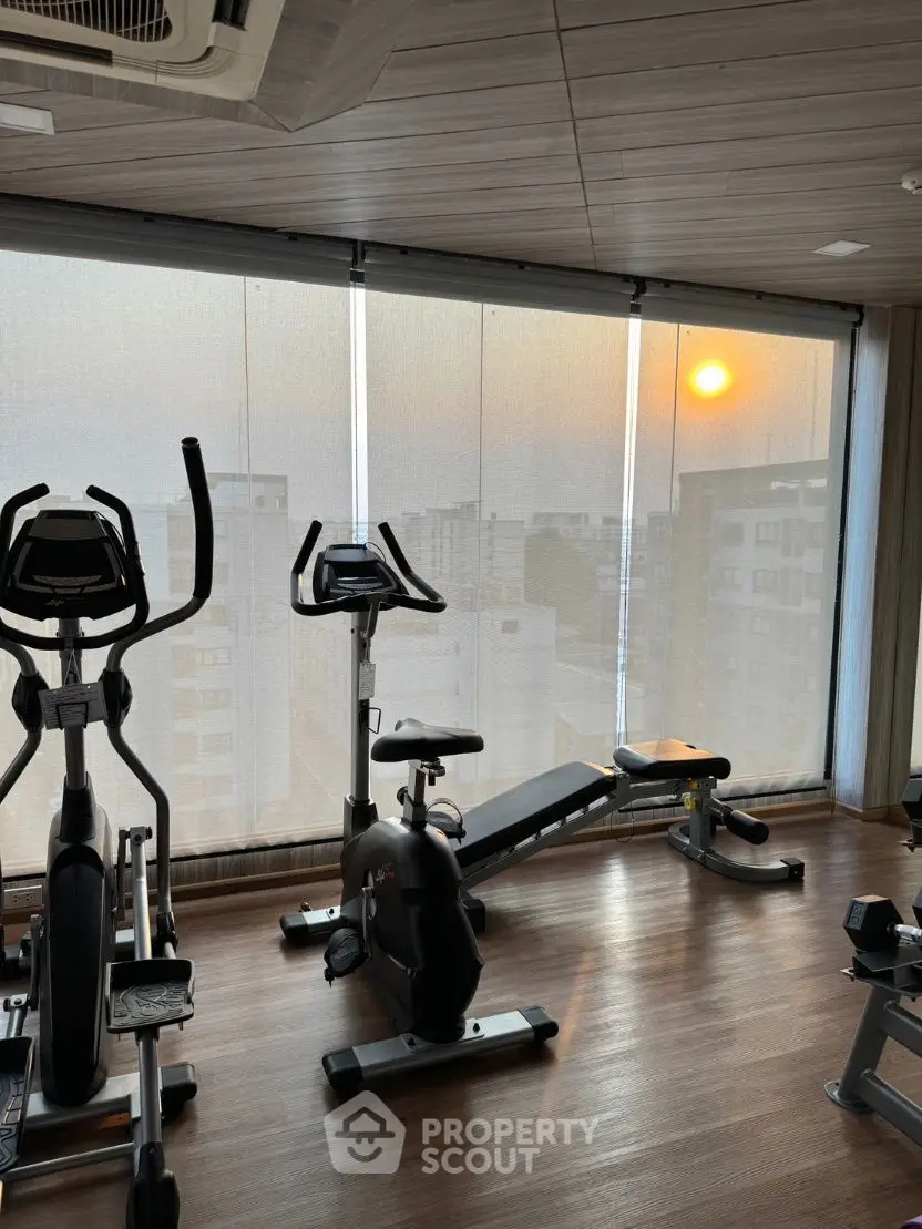 Modern gym with exercise equipment and city view at sunset