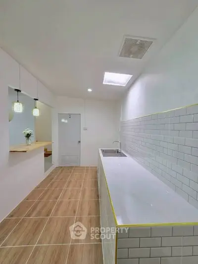 Modern kitchen with sleek design and open layout, featuring stylish lighting and tiled backsplash.