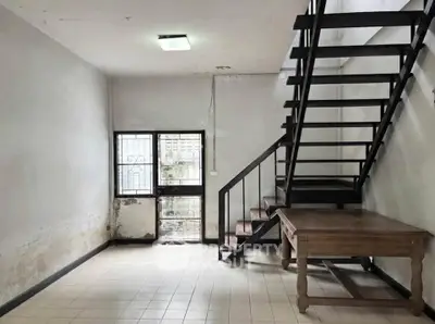 Spacious industrial-style room with metal staircase and wooden table, ideal for creative loft living.