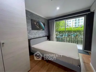 Modern bedroom with large window and garden view in stylish apartment.