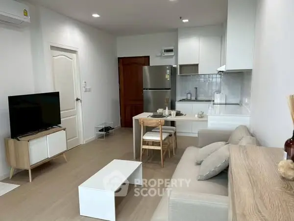Modern open-plan living room with cozy furniture and sleek kitchen area.