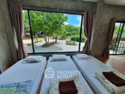 Spacious bedroom with large window offering serene garden view, featuring minimalist bedding and natural light.