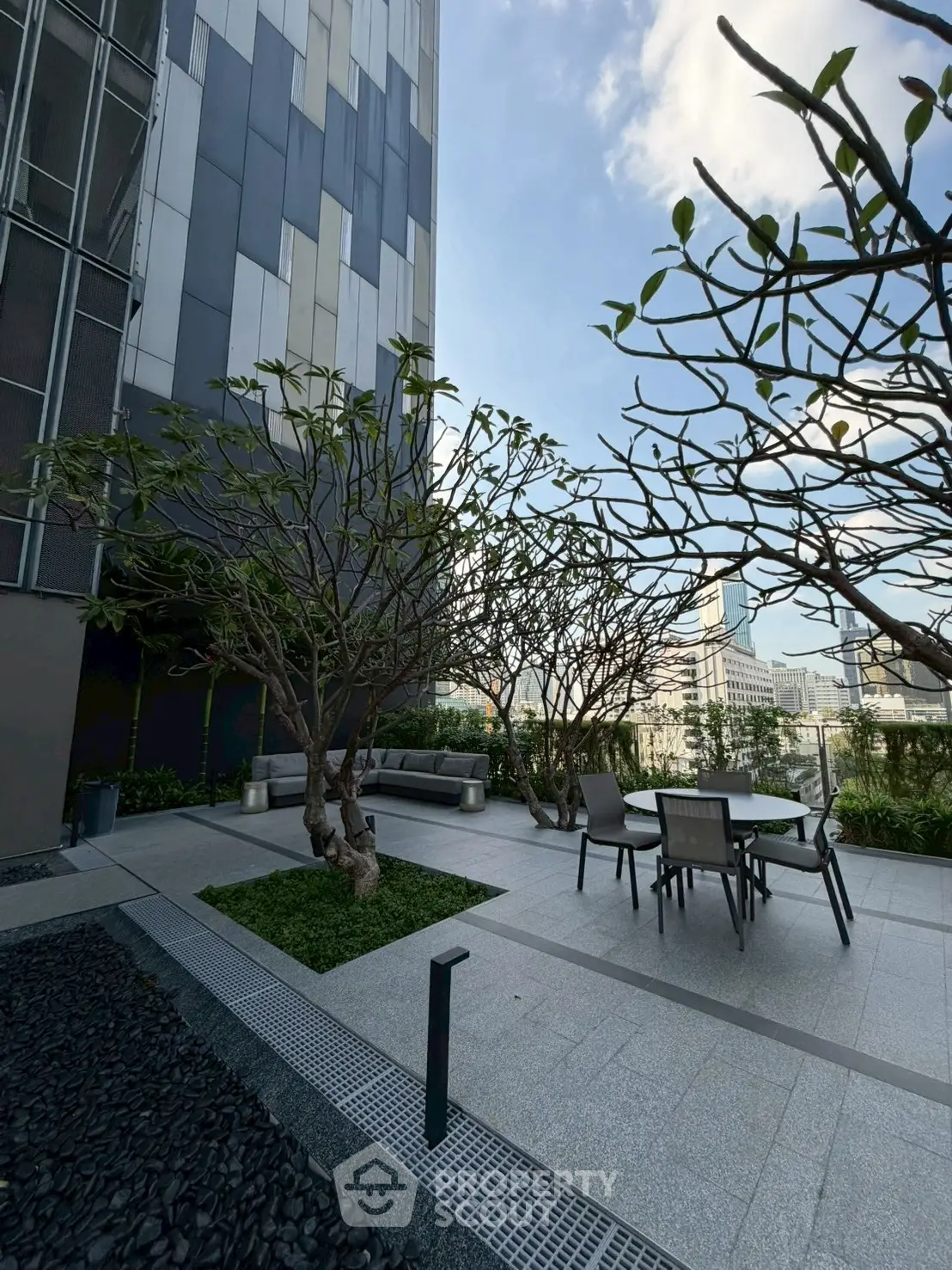 Modern rooftop garden with seating and city views, perfect for relaxation and gatherings.