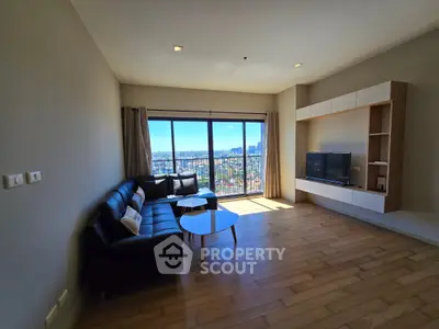 Spacious living room with large windows offering stunning city views, modern furniture, and wooden flooring.