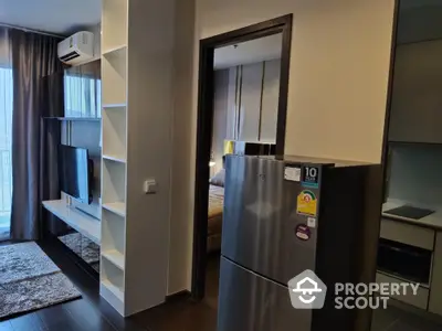 Modern studio apartment with sleek furniture and stainless steel fridge, showcasing a comfortable living space that seamlessly blends into a cozy bedroom area.