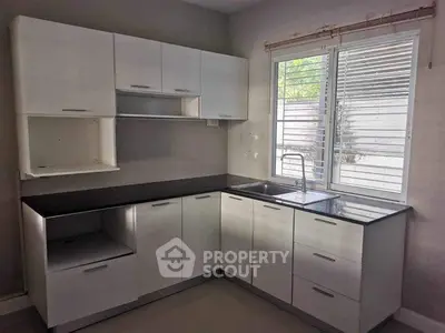 Modern kitchen with sleek cabinets and large window for natural light.