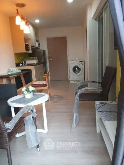 Modern open-layout kitchen and living area with washing machine and stylish furniture.