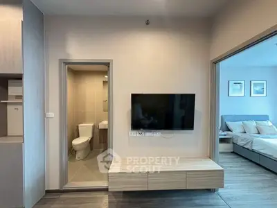 Modern apartment interior with wall-mounted TV, bathroom, and cozy bedroom view.