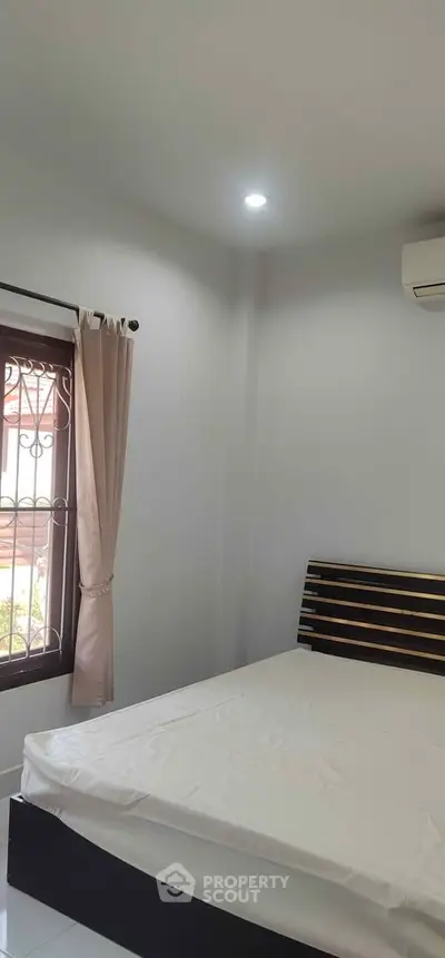 Cozy bedroom with natural light and modern air conditioning unit, perfect for relaxation.