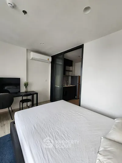 Modern bedroom with open layout to kitchen, featuring sleek furniture and minimalist design.