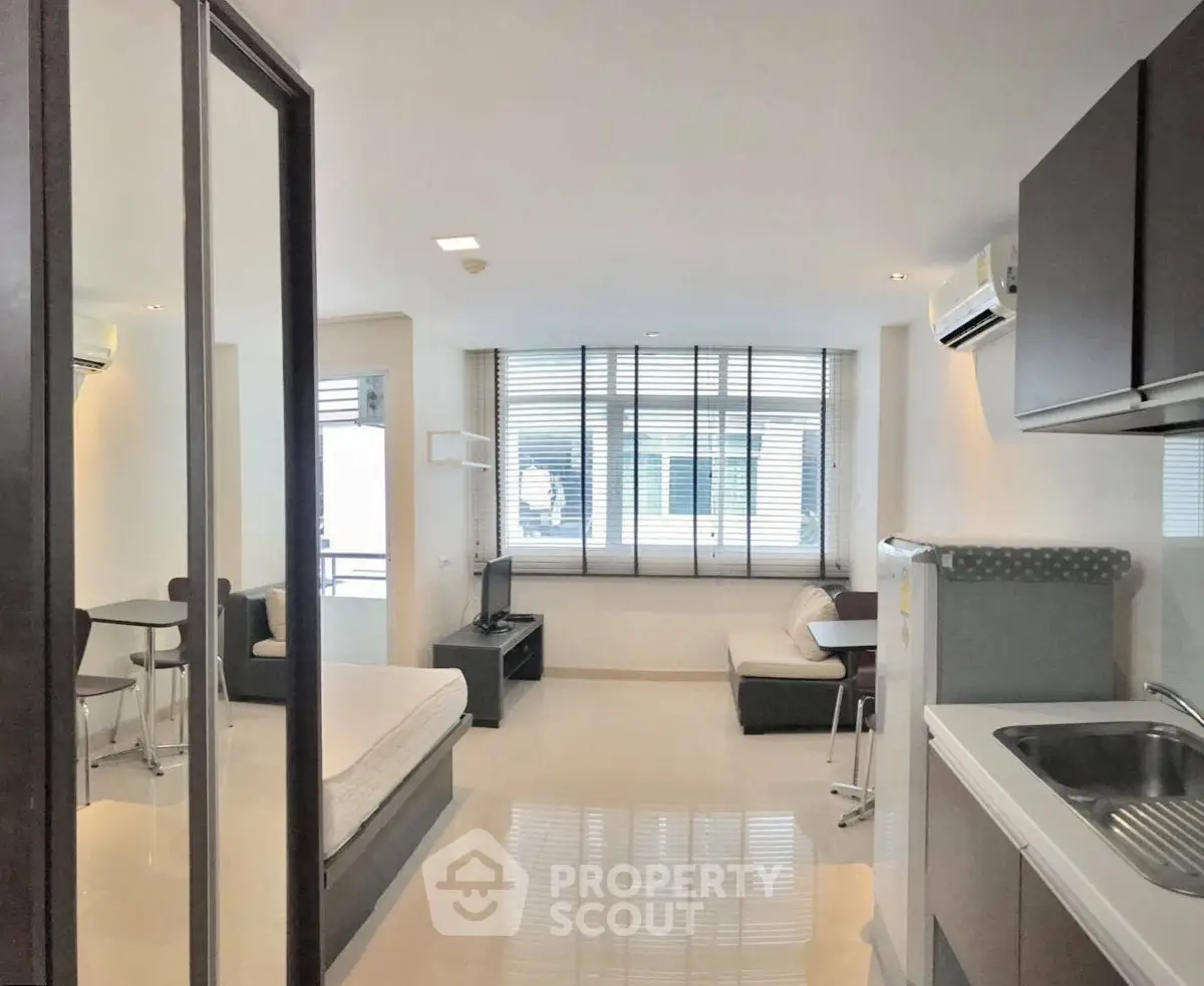 Modern studio apartment with open layout, featuring a cozy living area and compact kitchen.