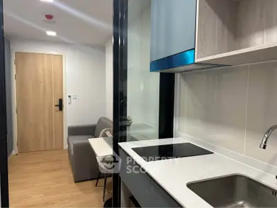 Modern compact kitchen with sleek design and cozy living area in a stylish apartment.