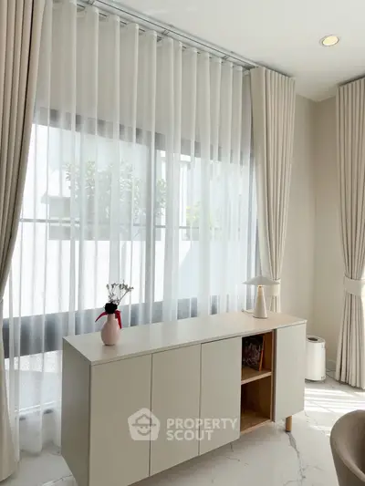 Elegant living room with natural light, sheer curtains, and modern decor in a stylish apartment.