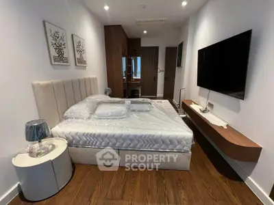 Modern bedroom with stylish decor, featuring a mounted TV and elegant wooden flooring.