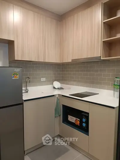 Modern kitchen with sleek cabinetry and electric cooktop in a compact layout.