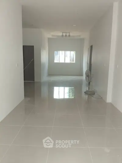 Spacious unfurnished room with glossy tiled floor and large window, ideal for customization.