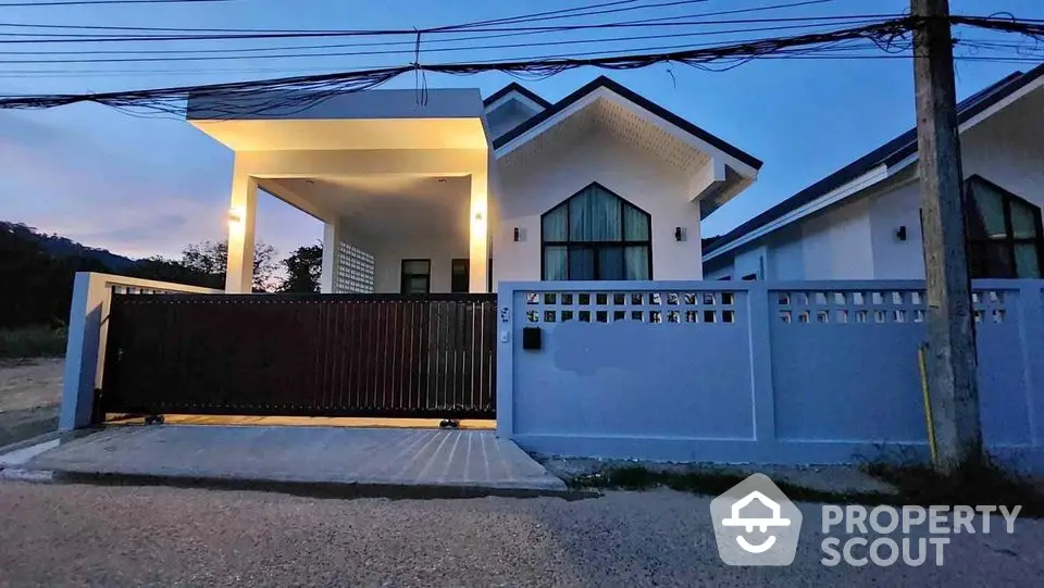 Modern single-story house with gated entrance and contemporary design at dusk.