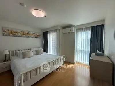 Spacious bedroom with natural light, modern decor, and wooden flooring in a stylish apartment.
