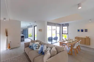 Spacious modern living room with open dining area and large windows offering natural light.