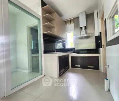 Modern kitchen with sleek cabinetry and glass door, featuring a stylish range hood.