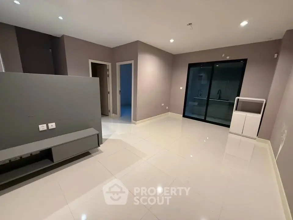Spacious modern living room with sleek tile flooring and neutral walls, ideal for contemporary living.