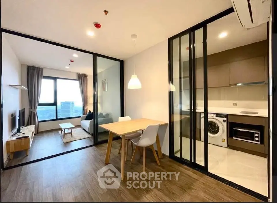 Modern open-plan living room with glass partitions, stylish kitchen, and city view.