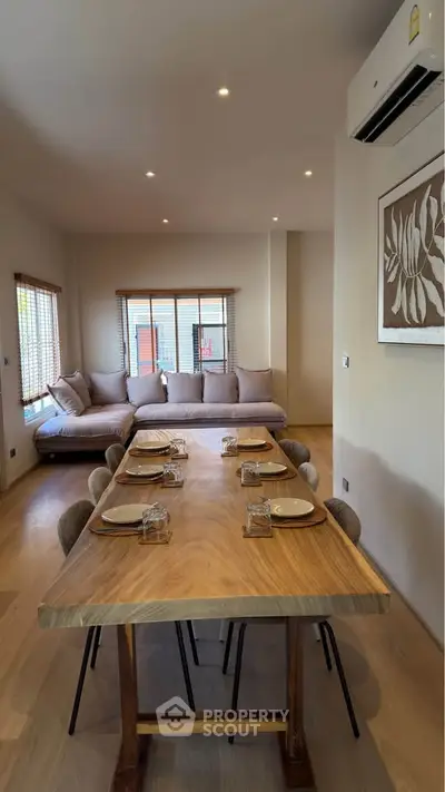 Modern living room with elegant dining area and cozy seating, featuring stylish decor and natural lighting.