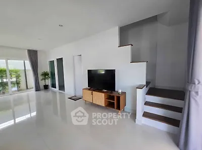Spacious modern living room with sleek staircase and large windows for natural light.