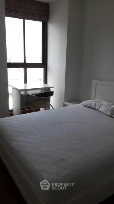 Cozy bedroom with large window and study desk, perfect for natural light lovers.