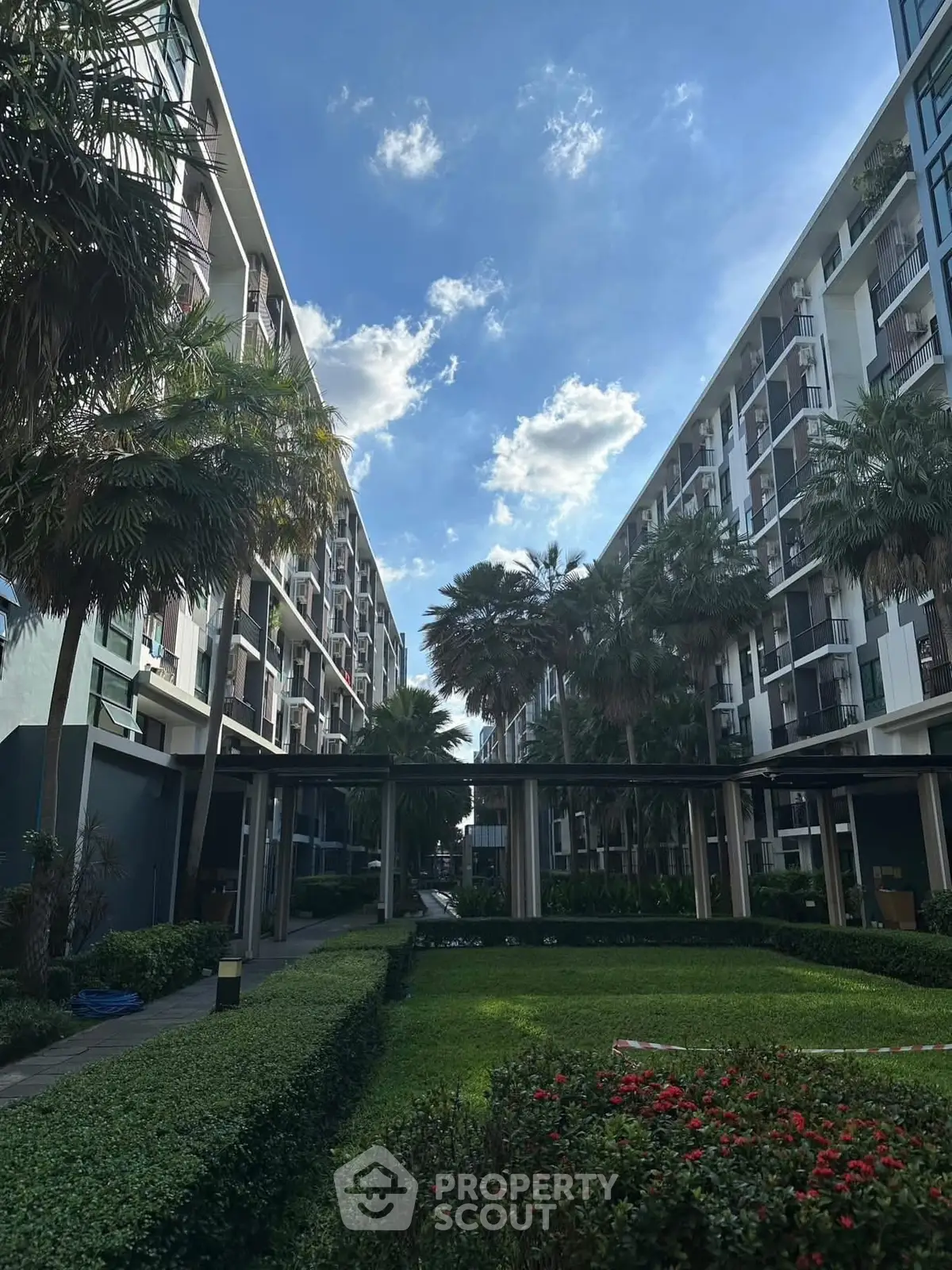 Modern apartment complex with lush garden and clear blue sky