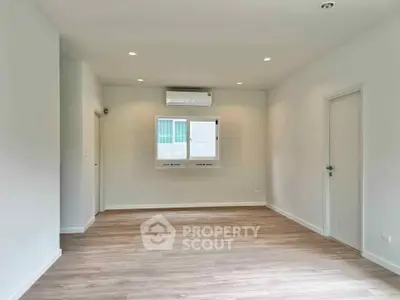 Spacious empty room with wooden flooring and air conditioning, perfect for customization.
