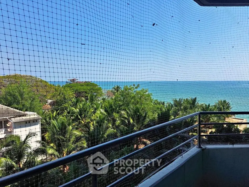 Stunning ocean view from a balcony with lush greenery and clear blue skies.