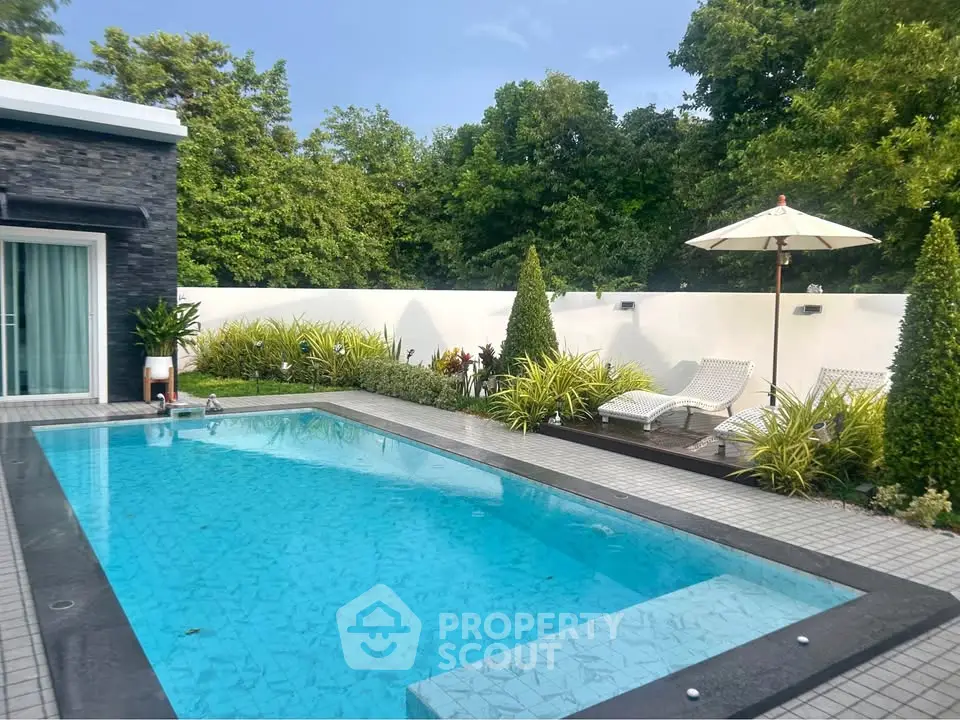 Luxurious private pool with lush greenery and modern patio furniture, perfect for relaxation and entertainment.