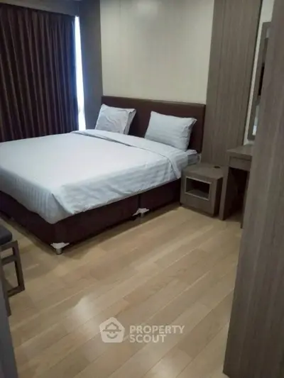 Modern bedroom with wooden flooring and elegant furnishings in a stylish apartment.