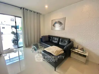 Modern living room with black leather sofa and white brick wall