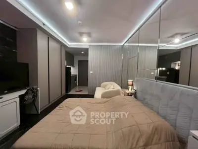 Modern bedroom with sleek design and ambient lighting, featuring a cozy bed and mirrored wall.