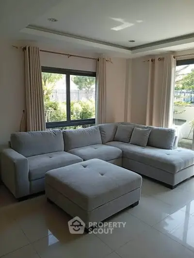 Spacious living room with modern grey sectional sofa and large windows.