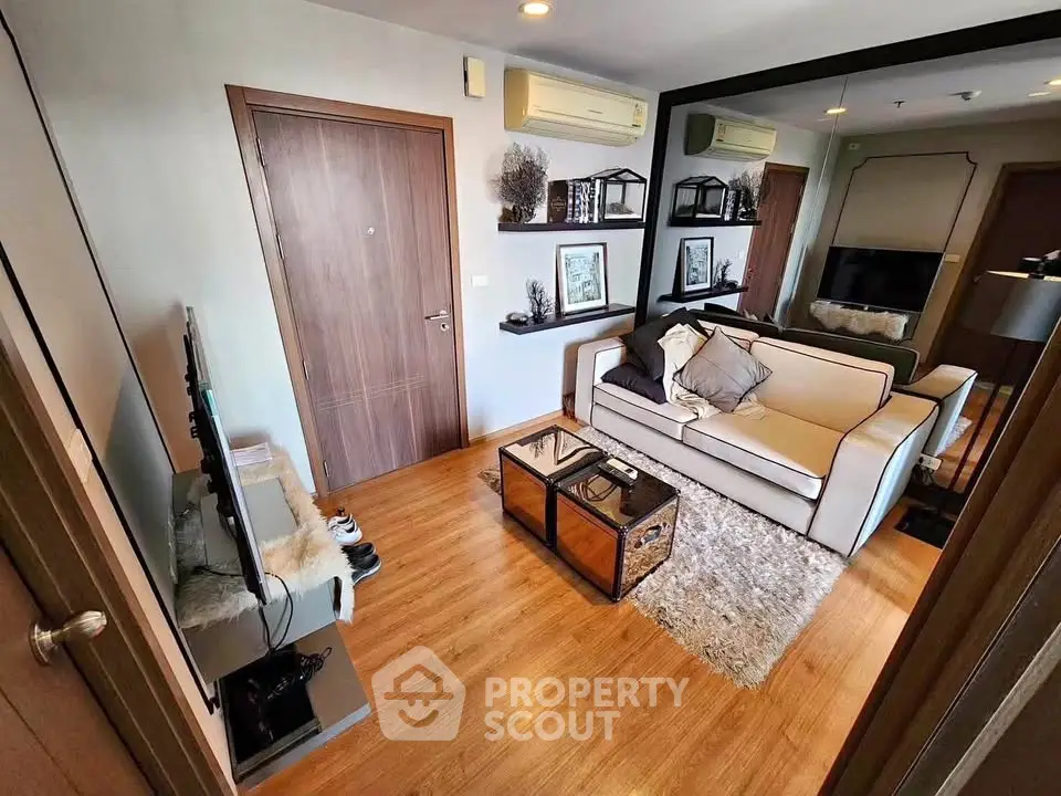 Modern living room with stylish decor and wooden flooring, featuring a cozy sofa and wall-mounted TV.