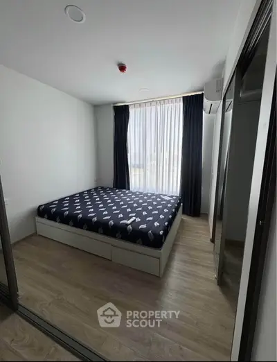 Modern bedroom with large window and stylish decor in a contemporary apartment.