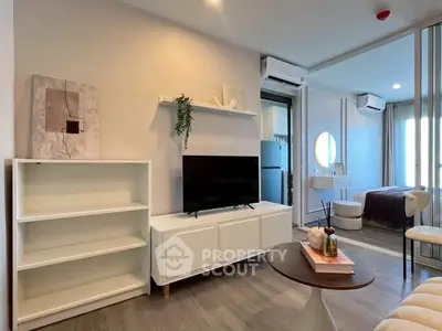 Modern living room with stylish decor and natural light, featuring a sleek TV stand and cozy seating area.