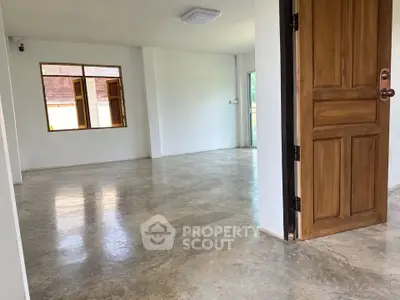 Spacious open-plan living area with polished concrete floors and wooden door, perfect for modern living.