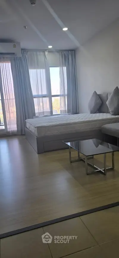 Spacious bedroom with modern decor and large windows offering natural light.