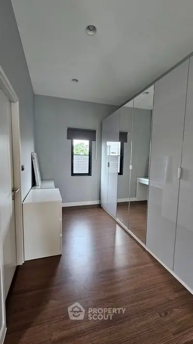 Modern bedroom with sleek mirrored wardrobe and wooden flooring