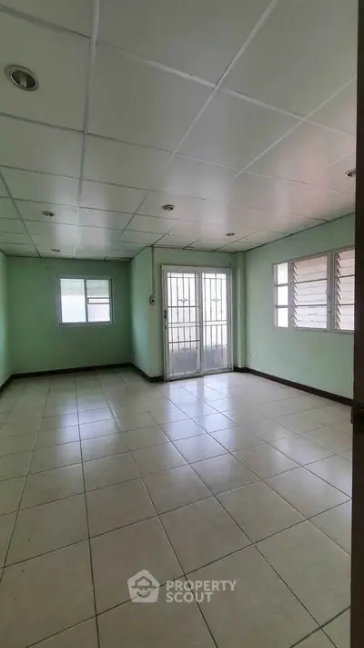 Spacious empty room with tiled floor and large windows, perfect for customization.