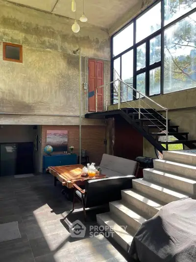 Stunning industrial-style living room with high ceilings and large windows, featuring modern furniture and a unique staircase.